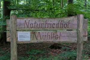In Holz geschnitzter Name: Naturfriedhof Mühltal